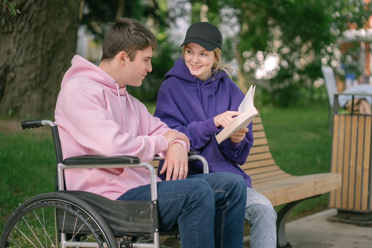 Couple sitting together on a park bench, reading a book and enjoying the day.