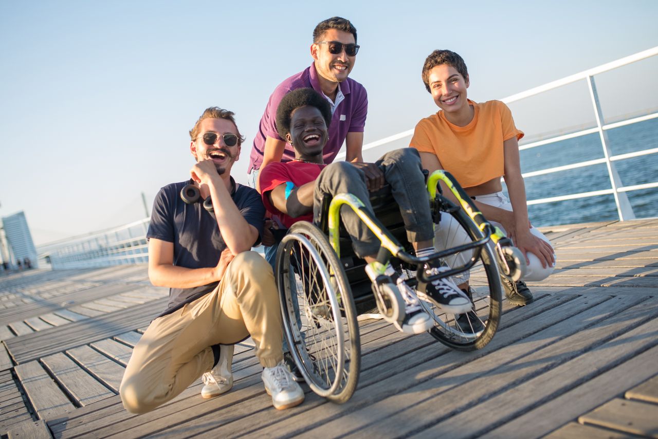 Group of friends with diverse backgrounds having fun by the water in Portugal, embracing inclusivity and joy.
