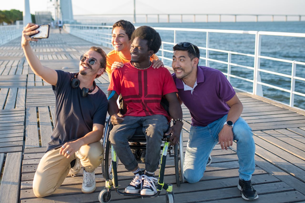 Diverse group of friends taking a selfie together on a waterfront boardwalk in Portugal.